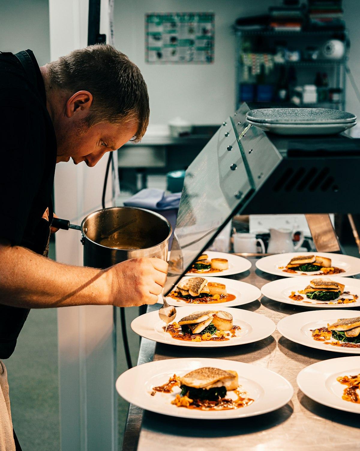 Chef plating multiple dishes during busy restaurant service