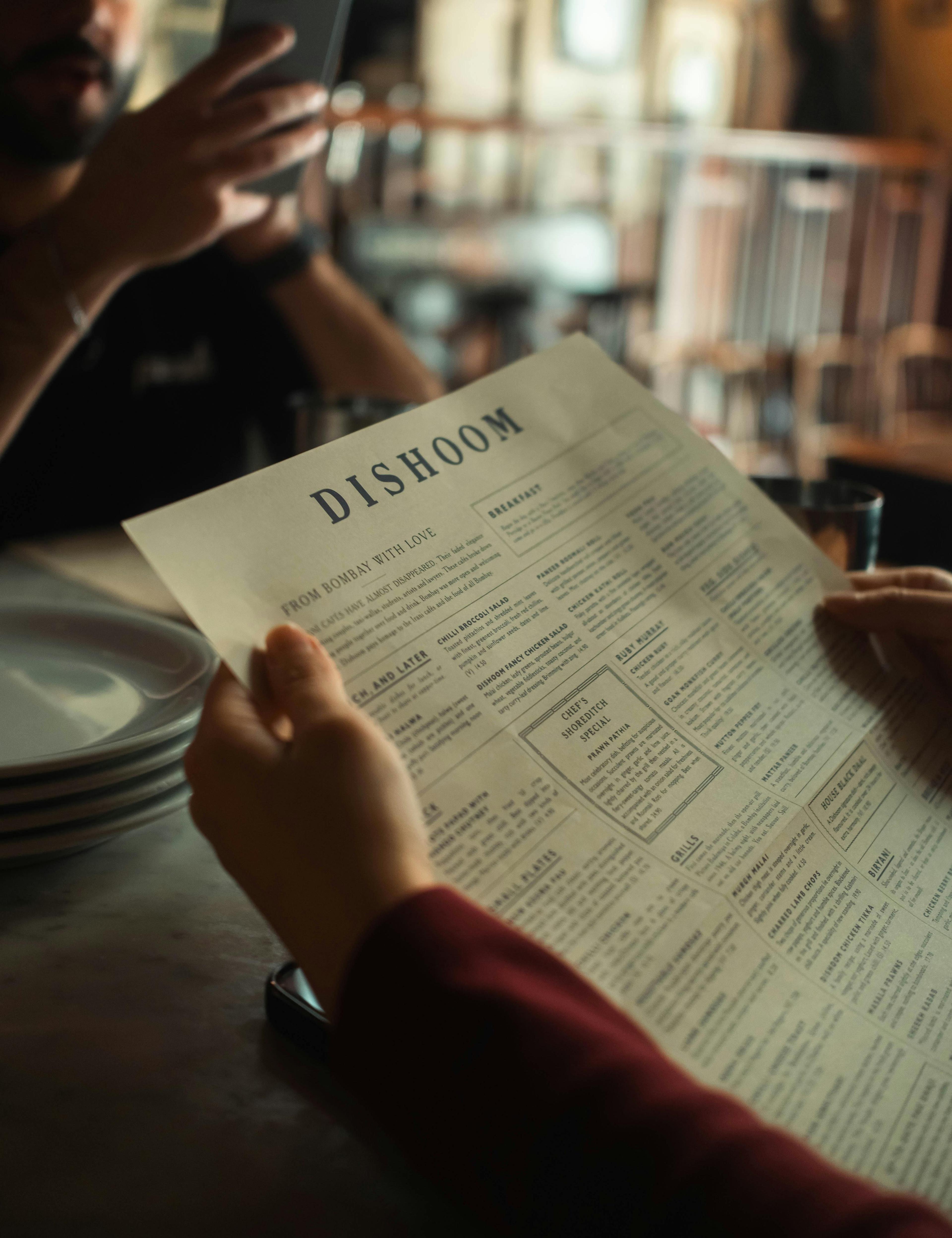 Diner reading a printed menu at a restaurant table